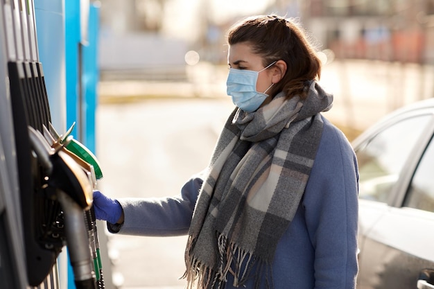 une jeune femme portant un masque médical à une station-service