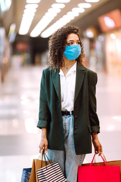 Jeune femme portant un masque de protection contre le coronavirus après le shopping.