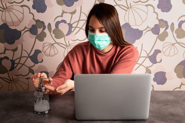 Jeune femme portant un masque, travaillant à la maison et se lavant les mains. Concept de coronavirus