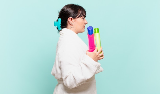 Jeune femme portant un peignoir sur la vue de profil cherchant à copier l'espace devant, pensant, imaginant ou rêvant