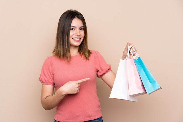 Jeune femme portant des sacs sur un mur isolé