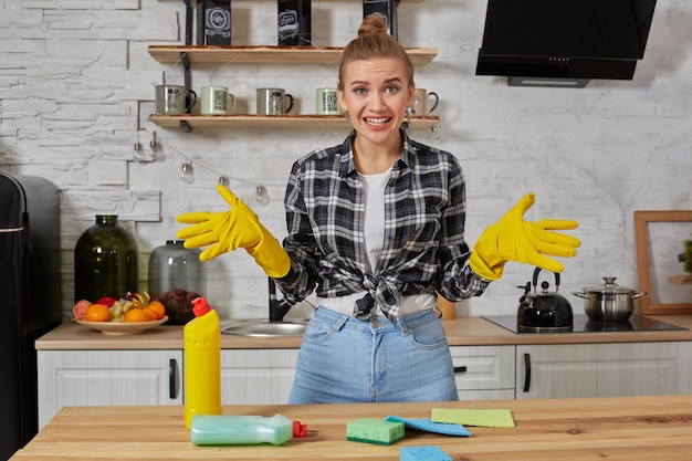 Jeune femme portant un tablier assis avec des tas d'éponges de nettoyage à l'intérieur