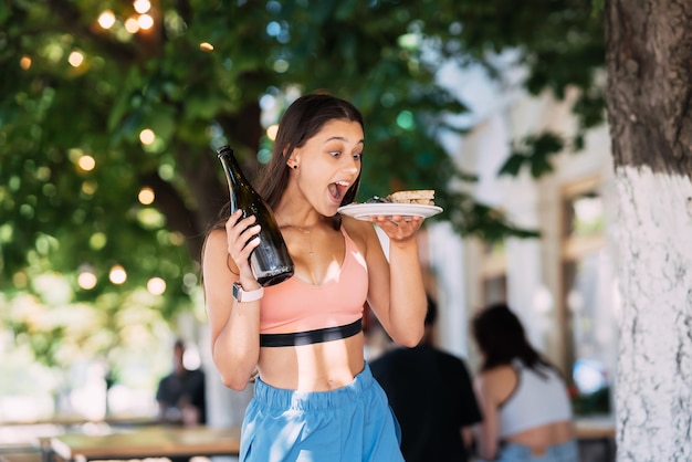 Jeune femme porte une assiette de collations et une boisson dans les mains