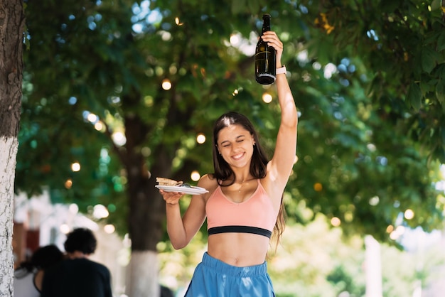 Jeune femme porte une assiette de collations et une boisson dans les mains