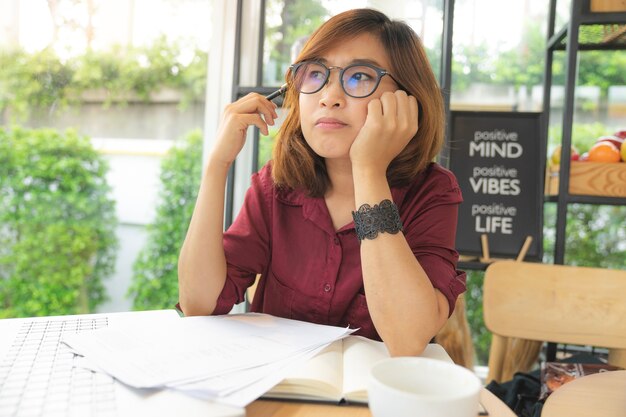 une jeune femme porte des lunettes de travail sur ordinateur portable et pense à l&#39;idée au café