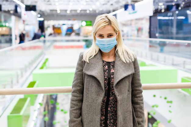 une jeune femme porte un masque de protection lors de ses achats au centre commercial. le concept de santé des maladies et de protection contre les virus.