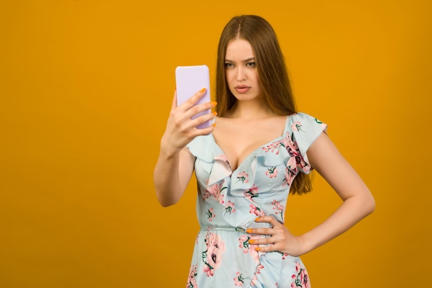 Jeune femme porte en robe sunner avec des fleurs surpris par les nouvelles sur un smartphone