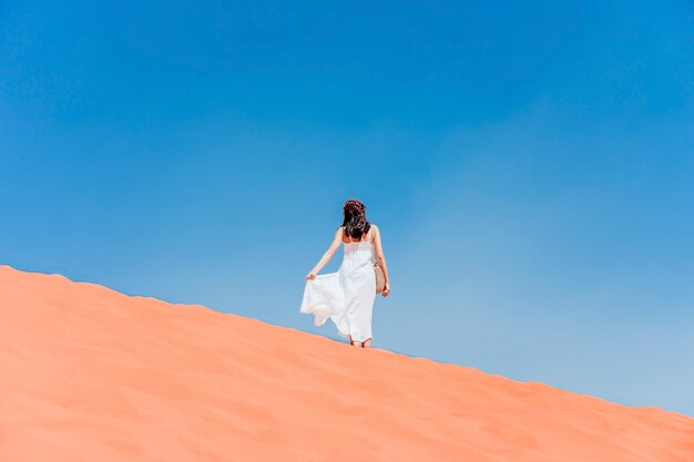 Une jeune femme posant sur la crête d&#39;une dune de sable rouge dans le désert de Wadi-Rum, Jordanie