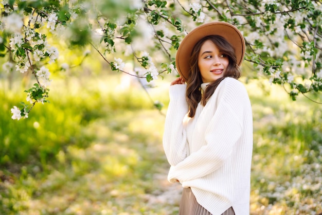 Jeune femme posant dans des fleurs de fleurs de printemps dans un jardin fleuri