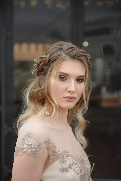 Jeune femme posant dans une robe longue en dentelle légère avec un bouquet de fleurs dans les mains