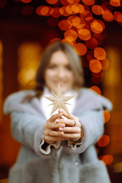 Jeune femme posant près de l'arbre de Noël aux vacances d'hiver avec l'étoile de Noël.