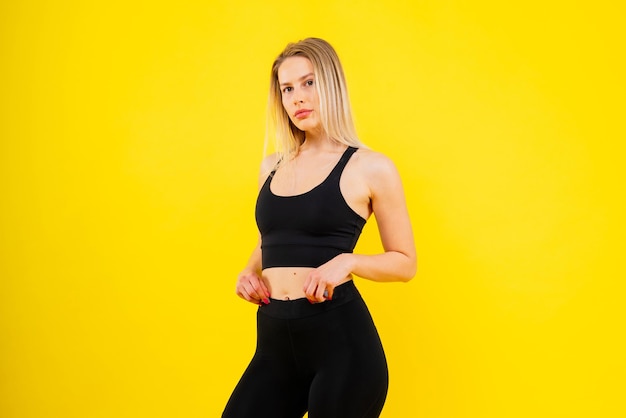 Une jeune femme pose dans le studio pour faire de la publicité sur les vêtements de sport et les vêtements de yoga, un style de vie sain et un sport.