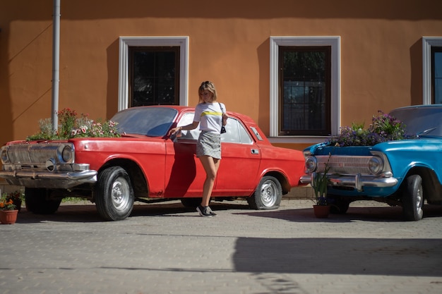 Une jeune femme pose devant une voiture abandonnée avec un jardin fleuri à la place du moteur