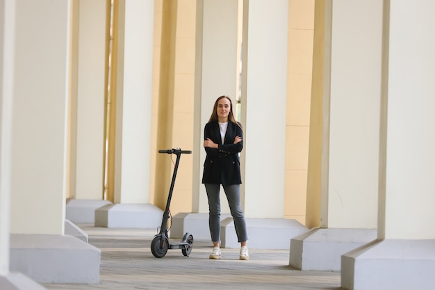 Une jeune femme pose près d'un scooter électrique dans la ville