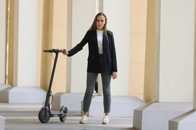 Une jeune femme pose près d'un scooter électrique dans la villeTransport moderne pour se déplacer dans la métropole