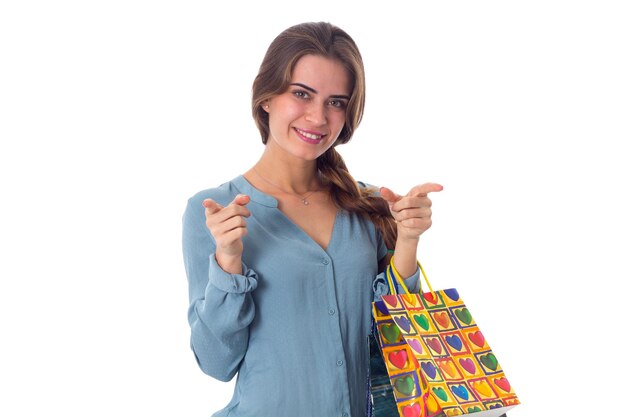 Jeune femme positive en blouse bleue tenant des sacs à provisions dans ses mains sur fond blanc en studio