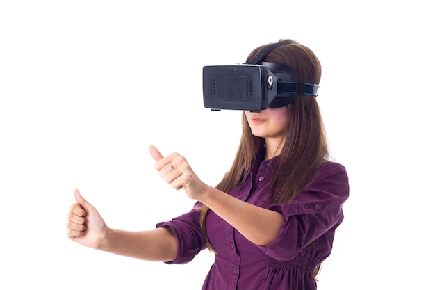 Jeune femme positive en blouse violette aux cheveux longs à l'aide de lunettes VR sur fond blanc en studio