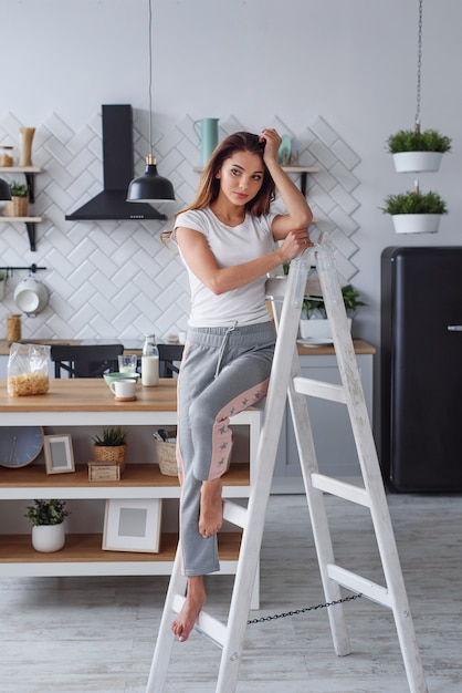 Jeune femme positive sur un escabeau en bois blanc