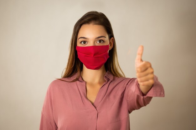 Jeune femme positive avec un masque rouge avec coup en studio