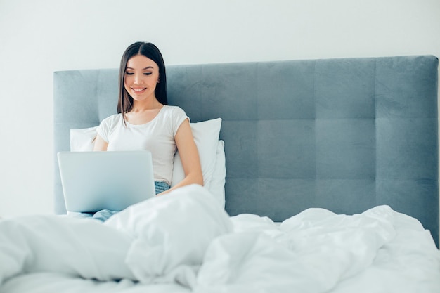 Jeune femme positive se détendre à la maison et souriant tout en regardant l'écran de l'ordinateur portable Bannière du site Web