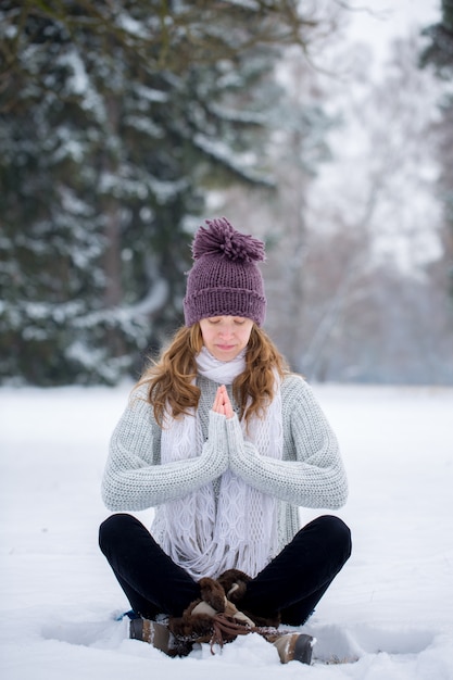 Jeune femme en posture de lotus dans la neige