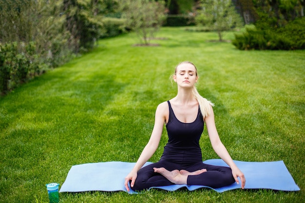 Jeune femme en posture de lotus dans le parc.