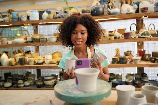 Jeune femme potier à la main faisant un vase en argile dans un atelier de poterie