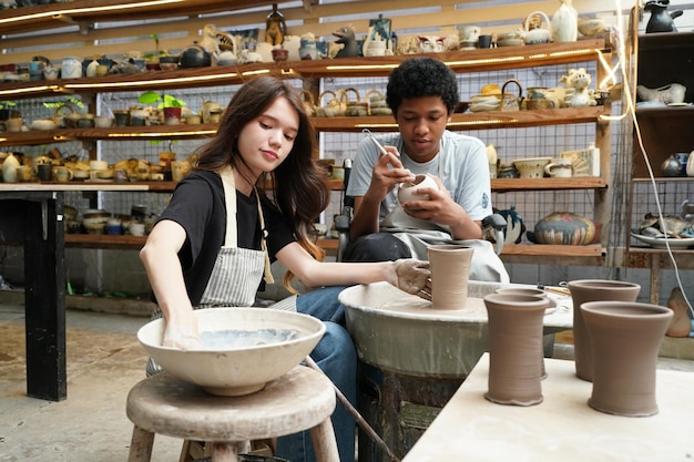 Jeune femme potier à la main faisant un vase en argile dans un atelier de poterie