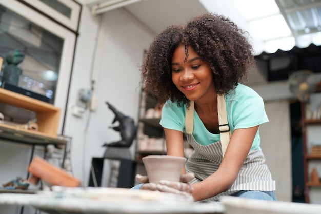 Jeune femme potier à la main faisant un vase en argile dans un atelier de poterie