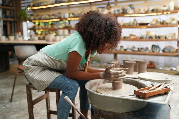 Jeune femme potier à la main faisant un vase en argile dans un atelier de poterie