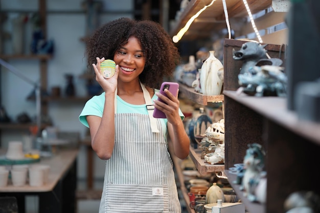 Photo jeune femme potier à la main faisant un vase en argile dans un atelier de poterie