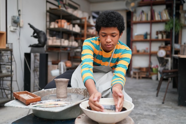 Jeune femme potier à la main faisant un vase en argile dans un atelier de poterie