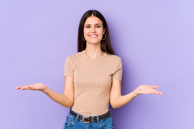 Jeune femme sur pourpre fait l'échelle avec les bras, se sent heureuse et confiante.