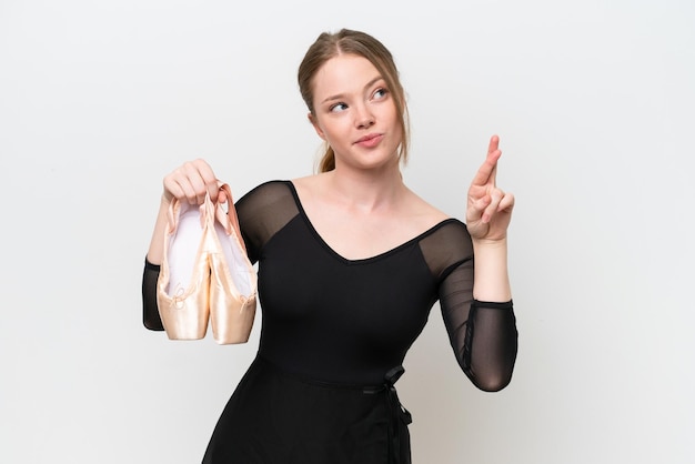 Jeune femme pratiquant le ballet isolé sur fond blanc avec les doigts croisés et souhaitant le meilleur