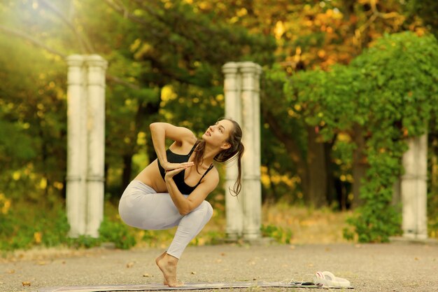 Jeune femme pratiquant l'équilibrage pose de yoga en plein air