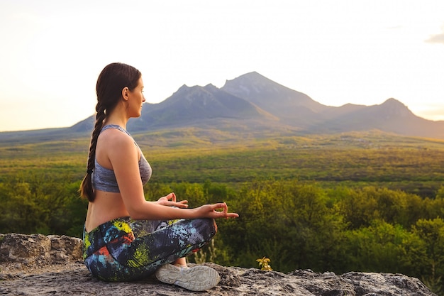 Jeune Femme Pratiquant Le Yoga Au Coucher Du Soleil Dans Un Endroit Magnifique Sur La Montagne.