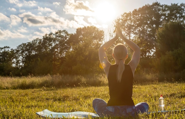 Jeune femme pratiquant le yoga au soleil du soir