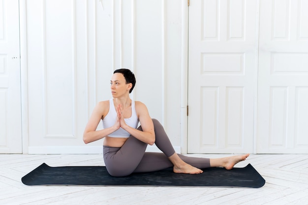 Jeune femme pratiquant le yoga dans un fond clair. Concept de mode de vie sain.