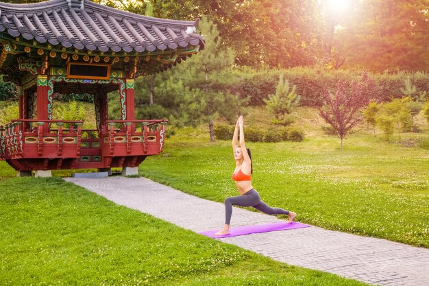 Jeune femme pratiquant le yoga dans le parc