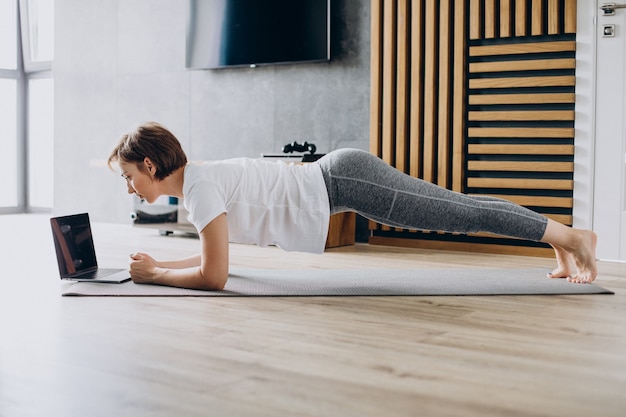 Jeune femme pratiquant le yoga à la maison sur le tapis