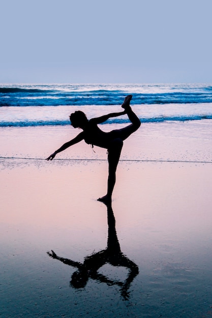 Photo jeune femme pratiquant le yoga sur la plage à agonda, goa, inde