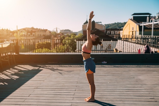 Jeune femme pratiquant le yoga sur le toit d'un immeuble