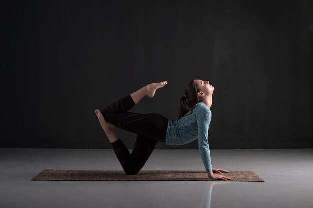 Jeune femme pratiquant le yoga travaillant à l'intérieur sur toute la longueur