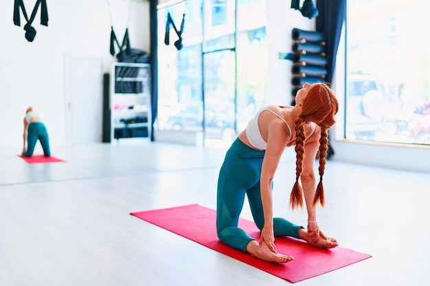 Photo une jeune femme pratique des exercices de dos sur un tapis dans un cours de yoga en studio.