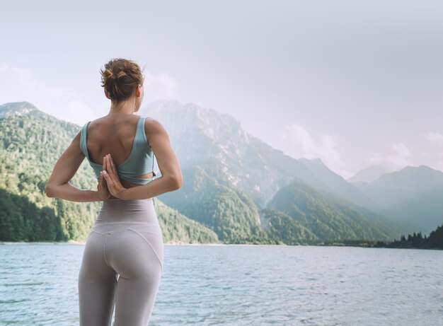 Jeune femme pratique le yoga au lac de montagne Fille faisant du yoga sur la nature Modes de vie sains