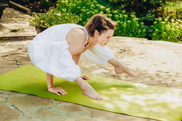 Jeune femme pratique le yoga dans la cour d'une maison de campagne
