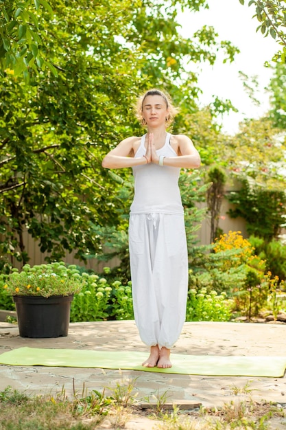Jeune femme pratique le yoga dans le jardin d'été Namaskar Mudra