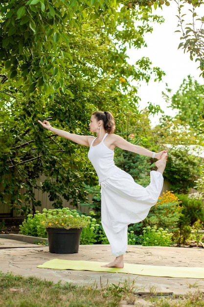 Jeune femme pratique le yoga dans le jardin d'été Natarajasana Lord of the Dance Pose ou Dancer Pose