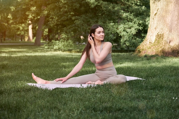 Une jeune femme pratique le yoga dans un parc de la ville par une chaude journée d'été