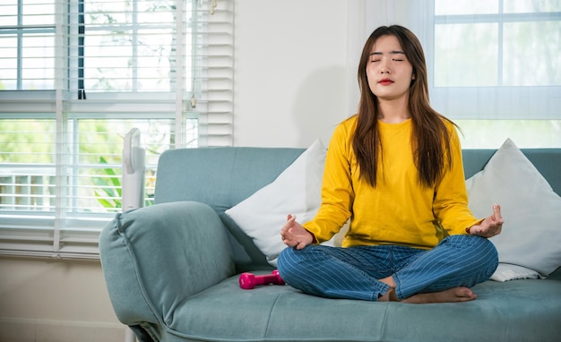 Une jeune femme pratique le yoga et la méditation en position de lotus.